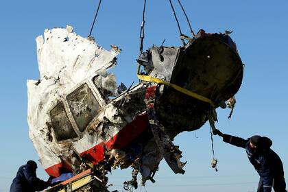 Operarios transportan un pedazo de los restos del vuelo 