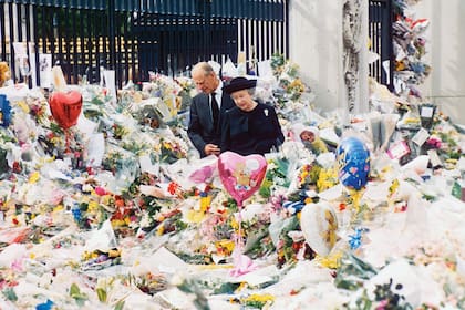 En 1997, junto a su marido, mirando las ofrendas florales y los mensajes con los que el pueblo despidió y lloró a Diana en Buckingham. 