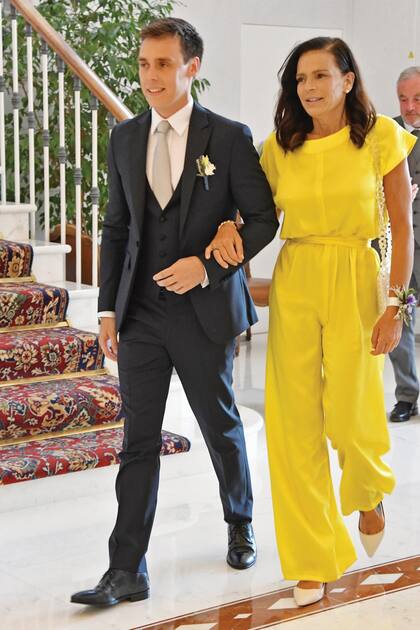 La princesa del brazo de su hijo. Estefanía vestida con un mono color amarillo intenso y una pulsera floral, un guiño al diseño y al ramo de la novia.