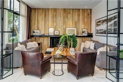 La planta baja fue recientemente redecorada por el equipo creativo de Negro House Pleasures. En el living, se sumó el hierro, la madera de kiri y el color negro. En la pared del fondo se ven cuadros como el que tiene el tratado de la Torre Eiffel y un mapa, comprados durante un viaje a París.