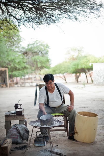 El indio Froilán en su patio termina un bombo. 