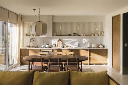 Mesa ‘Petrona’, sillas ‘Lalo’, muebles de cocina enchapados en petiribí y revestimiento de varillas de kiri pintadas (todo de Talleres Sustentables). La heladera se alojó detrás de la puerta de madera.