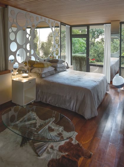 Como un guiño pop, una constelación de espejos circulares “enmarca” la cama, vestida por textiles y almohadones de Good Luck Casa.