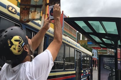 A bordo de su bicicleta Diego pega carteles de vinilo autoadhesivos donde los originales están rotos o ausentes