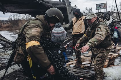 07/03/2022 Unos soldados ayudan a cruzar el río a un niño, a 7 de marzo de 2022, en Irpin (Ucrania). POLITICA Diego Herrera - Europa Press