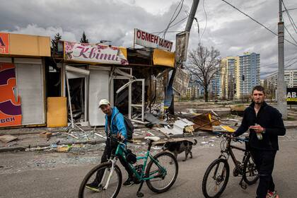17 de abril de 2022, Ucrania, Kharkiv: Dos hombres pasan por delante de un edificio dañado tras un ataque ruso a la ciudad.
