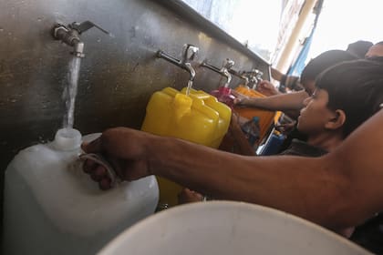 Los palestinos llenan contenedores con agua potable desde un vehículo de distribución de agua, en medio de la crisis hídrica provocada por el asedio israelí a la Franja de Gaza