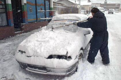 1998: Durante una fuerte nevada en el centro de Ushuaia, Oscar Benítez, intenta sacar la nieve del parabrisas con un secador