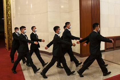 Un grupo de guardias de seguridad camina en el Gran Salón del Pueblo.