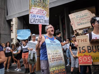23 de agosto de 2019, Italia, Mailand: las personas sostienen pancartas mientras participan en una protesta contra el presidente brasileño Jair Bolsonaro por los incendios forestales en la región amazónica
