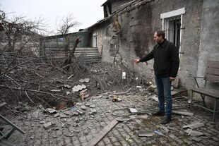 25-02-2022 Un hombre muestra el cráter de la explosión de un proyectil en su patio tras un reciente bombardeo, en Donetsk, República Popular de Donetsk. POLITICA Ilya Pitalev / Sputnik / ContactoPhoto