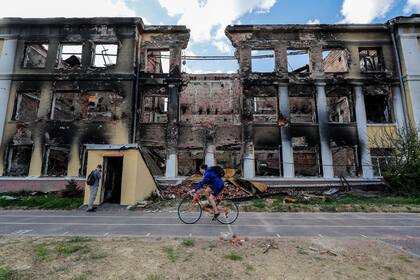 26 April 2022, Ukraine, Kharkiv: A cyclist rides past the remains of school damaged by Russian air strikes, amid the Russian invasion of Ukraine. Photo: Daniel Ceng Shou-Yi/ZUMA Press Wire/dpa