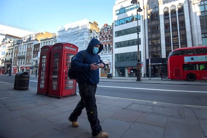 26 de marzo de 2020, Inglaterra, Londres: un hombre con una máscara facial protectora camina durante la hora pico, después de que el primer ministro Boris Johnson pusiera el Reino Unido bajo llave para ayudar a frenar la propagación del coronavirus (COVID-19).