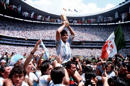 29 de junio de 1986: "Un momento icónico de la carrera de Maradona: cargado a hombros tras la final de la Copa del Mundo en el Azteca en 1986. En medio de un tumulto de fanáticos, periodistas y fotógrafos, se puede ver cómo los espectadores y los hinchas tiran su camiseta y hacen todo lo posible por tocarlo; todo el mundo quiere un pedazo de Diego".

