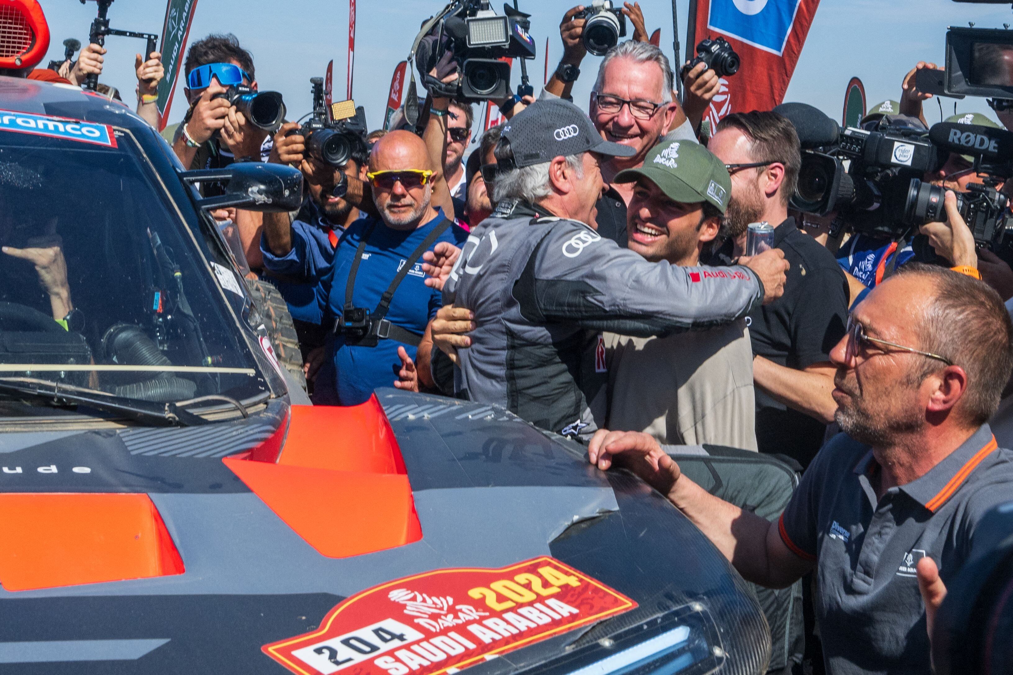 Se abrazan los dos Carlos Sainz, celebrando la victoria del padre con Audi en el Rally Dakar 2024; la marca alemana desembarcará en 2026 en Fórmula 1 y tentó al piloto de 29 años para ser su conductor principal.
