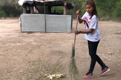 Camila Romero, de 13 años, es la encargada de barrer las hojas en su casa, en la comunidad de Piruaj Bajo, en Santiago del Estero. Las apila para después juntarlas con la mano y llevarlas a un pozo en donde las queman.