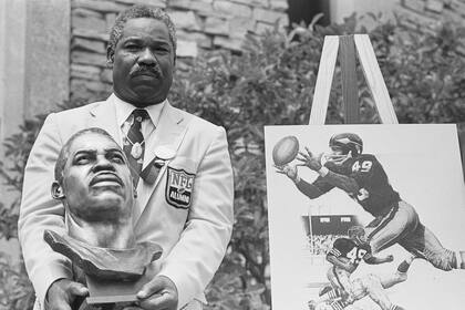 30 de julio de 1983: el ex mediocampista y receptor abierto de Cleveland Browns y Washington Redskins Bobby Mitchell posa con su busto de bronce después de ser incluido en el Salón de la Fama del Fútbol Profesional.