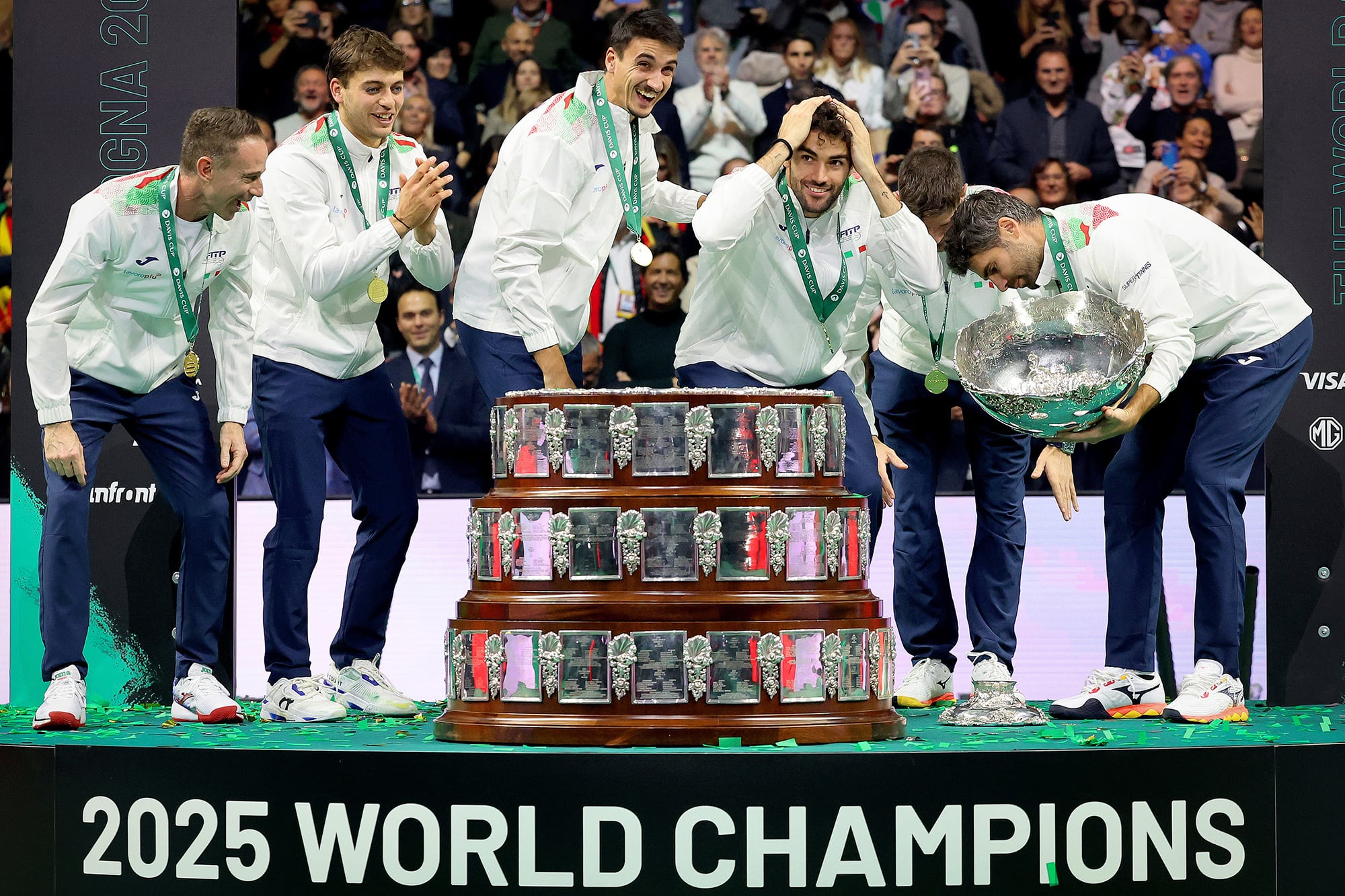 Los miembros del equipo italiano de Copa Davis reaccionan cuando Simone Bolelli deja caer la base del trofeo durante la celebración de su tercer título consecutivo en la Final de 2025 en Bolonia