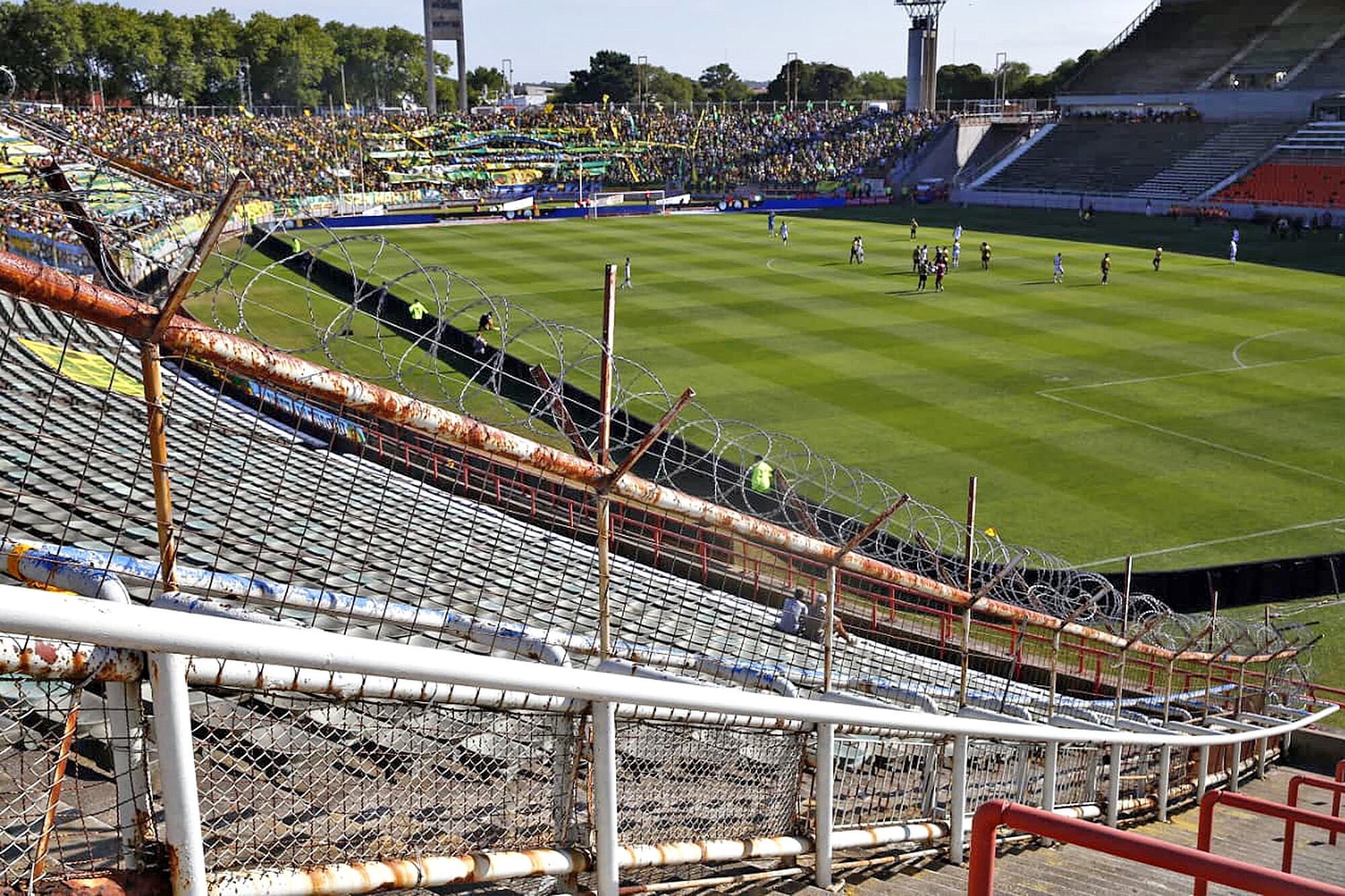 El deterioro de los alambrados de frente; de fondo, el estadio y el público que fue a ver el primer partido del campeonato