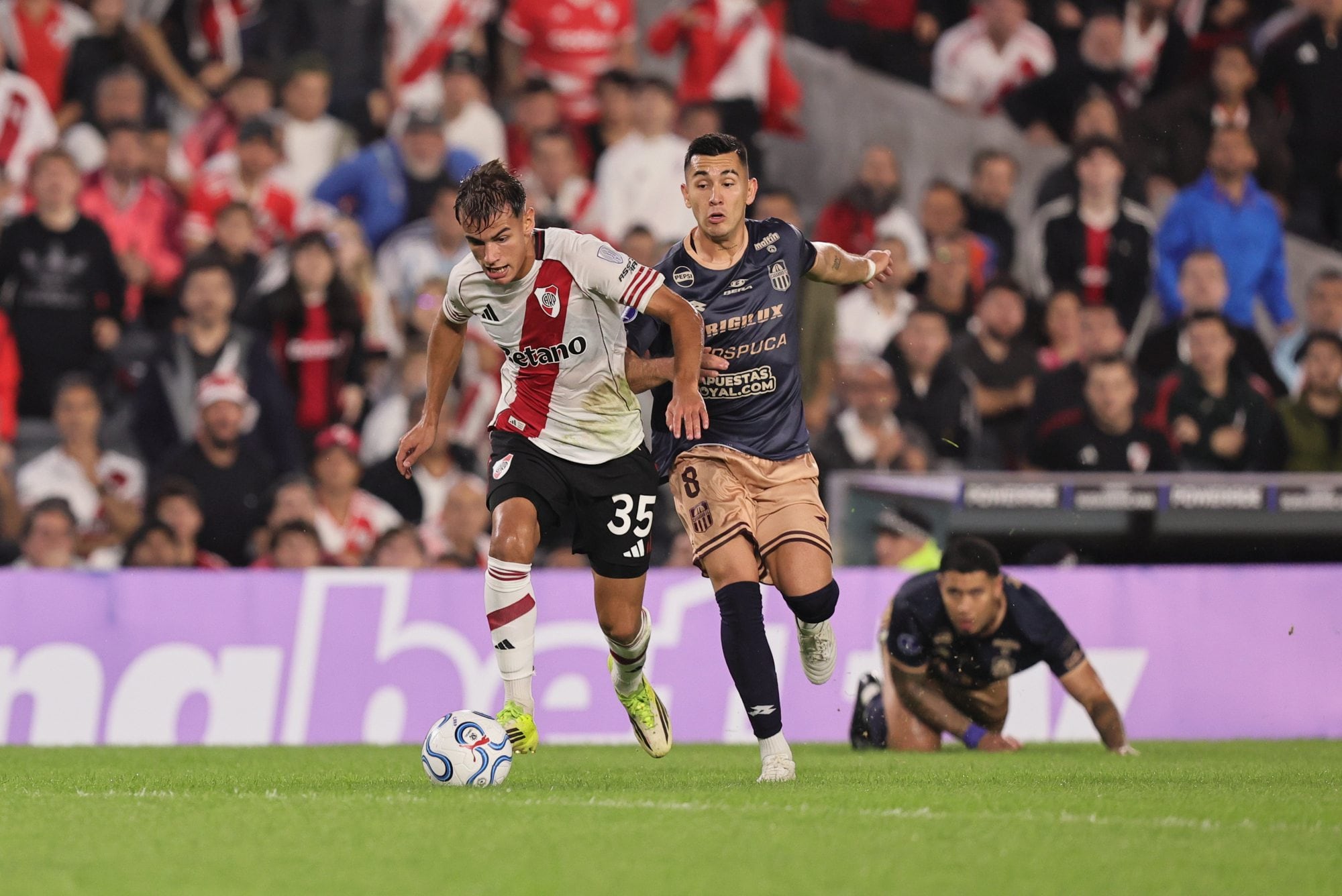 Joaquín Freitas lleva la pelota, seguido por Juan Pérez