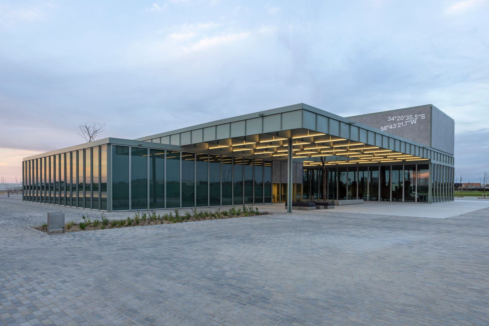 El edificio transparente, con tres cuerpos, sin entrada principal, sin vestíbulo y sin nombre en su fachada, solo las coordenadas geográficas