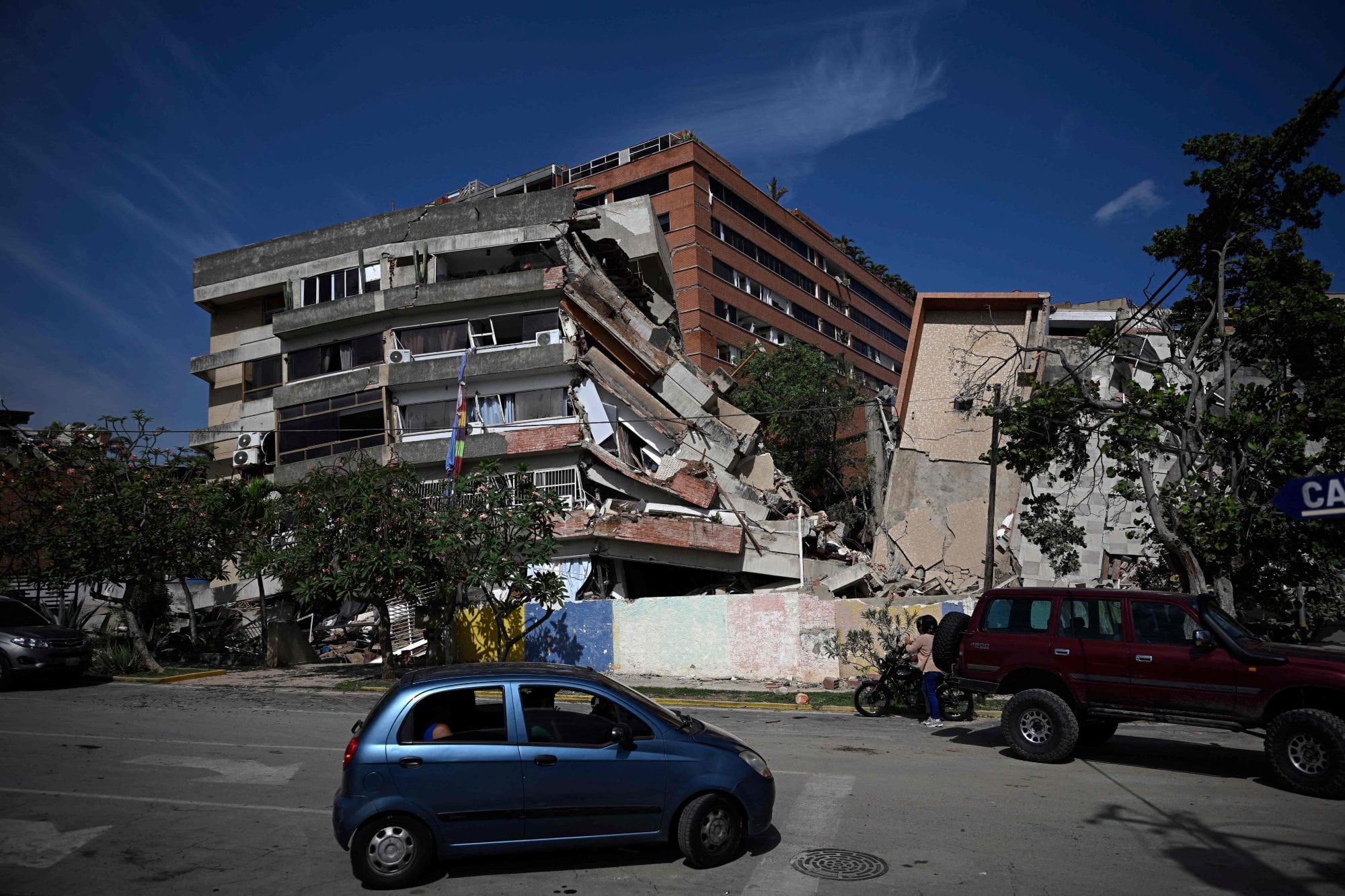 Un automóvil circula frente a edificios derrumbados tras un terremoto en Catia La Mar, estado La Guaira
