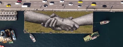 Una vista aérea muestra una obra del artista callejero franco-suizo Saype llamada "Beyond Walls" en una barcaza flotante sobre el Cuerno de Oro en Estambul, Turquía