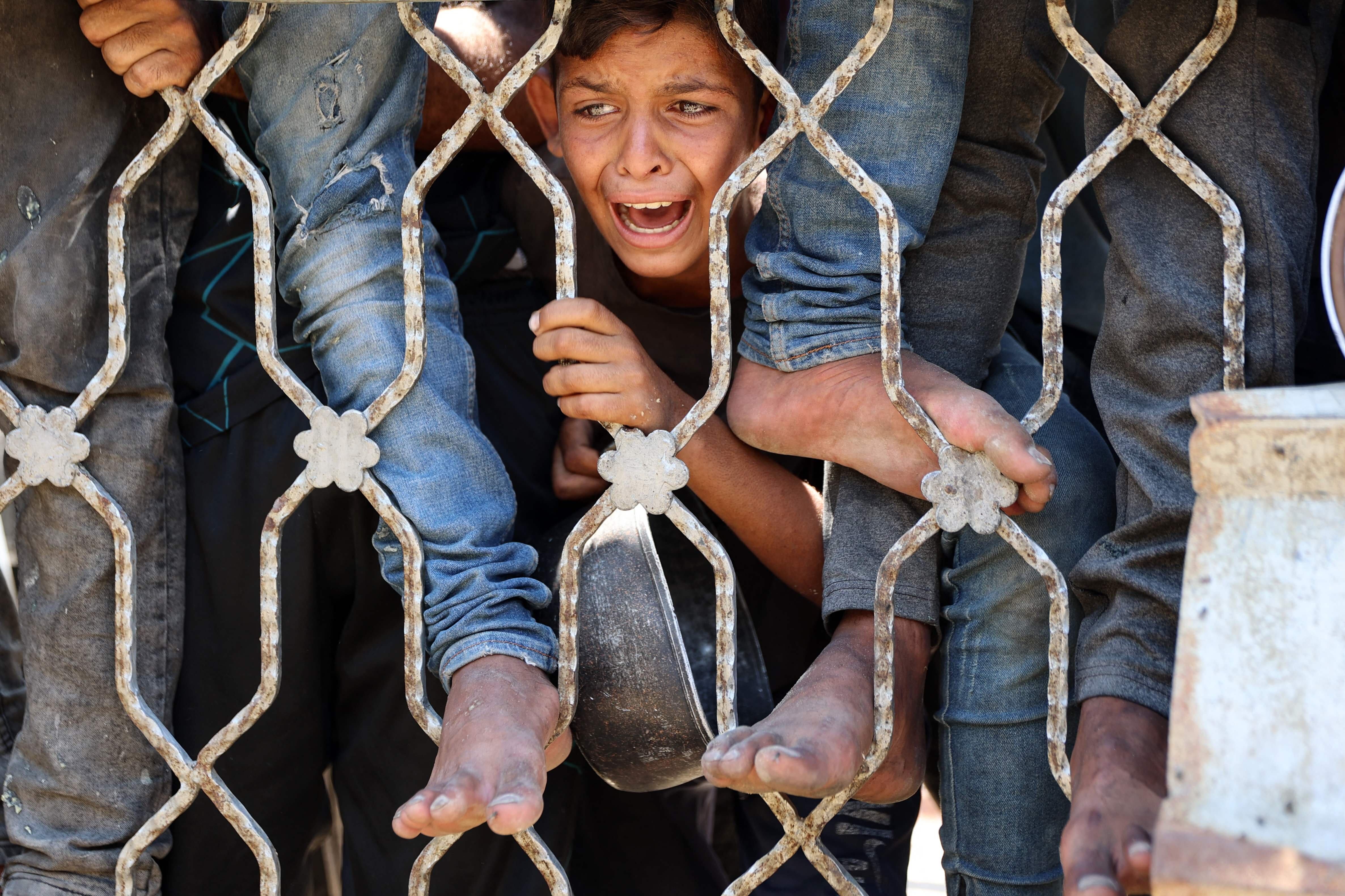 Un niño palestino reacciona mientras espera en un punto de distribución de sopa de lentejas en la ciudad de Gaza, en el norte de la Franja de Gaza, el 27 de julio de 2025