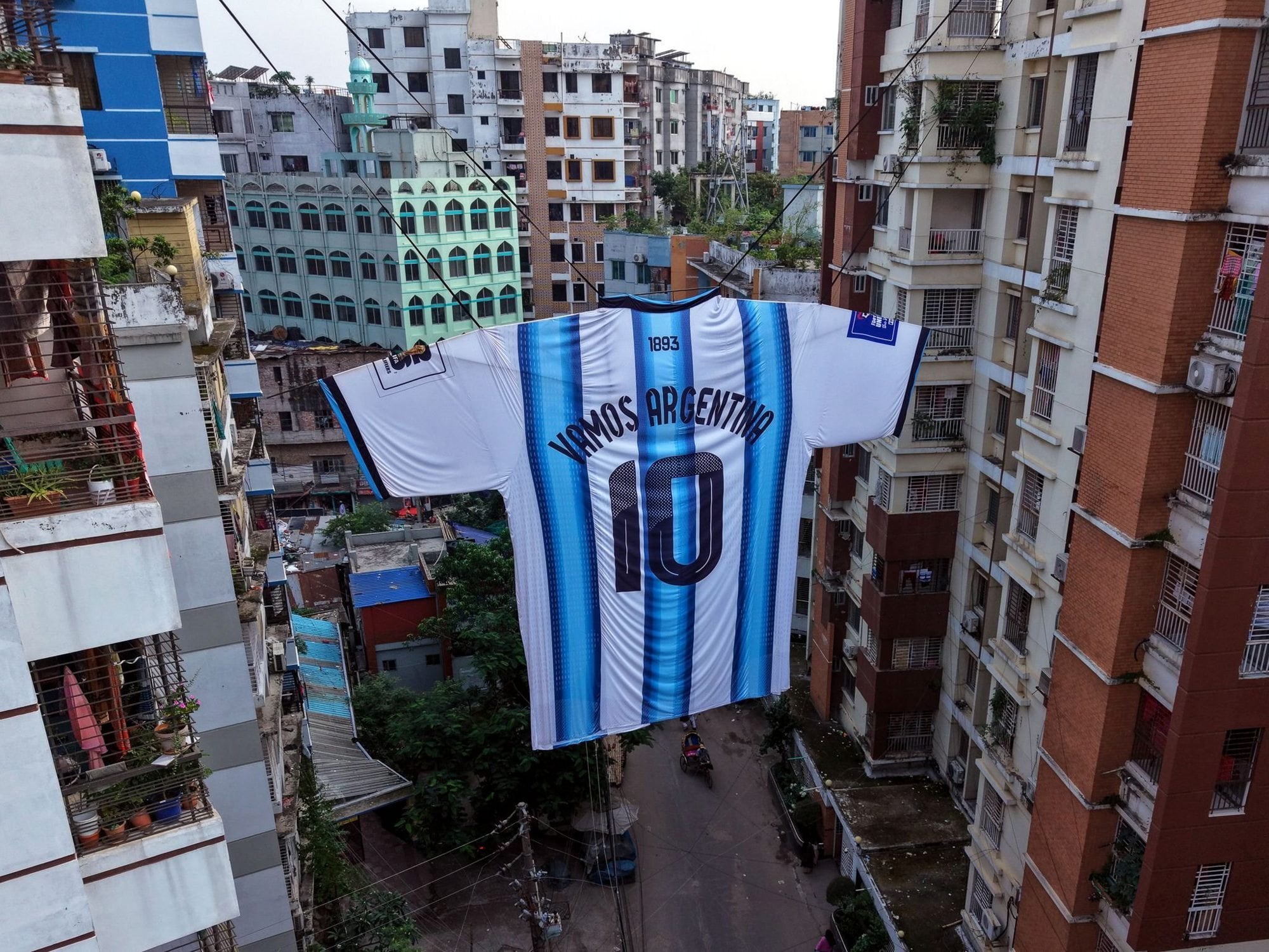 Una camiseta gigante de la selección nacional de fútbol de Argentina, dedicada a Lionel Messi, cuelga entre dos edificios de apartamentos en el área de Ibrahimpur de Dhaka