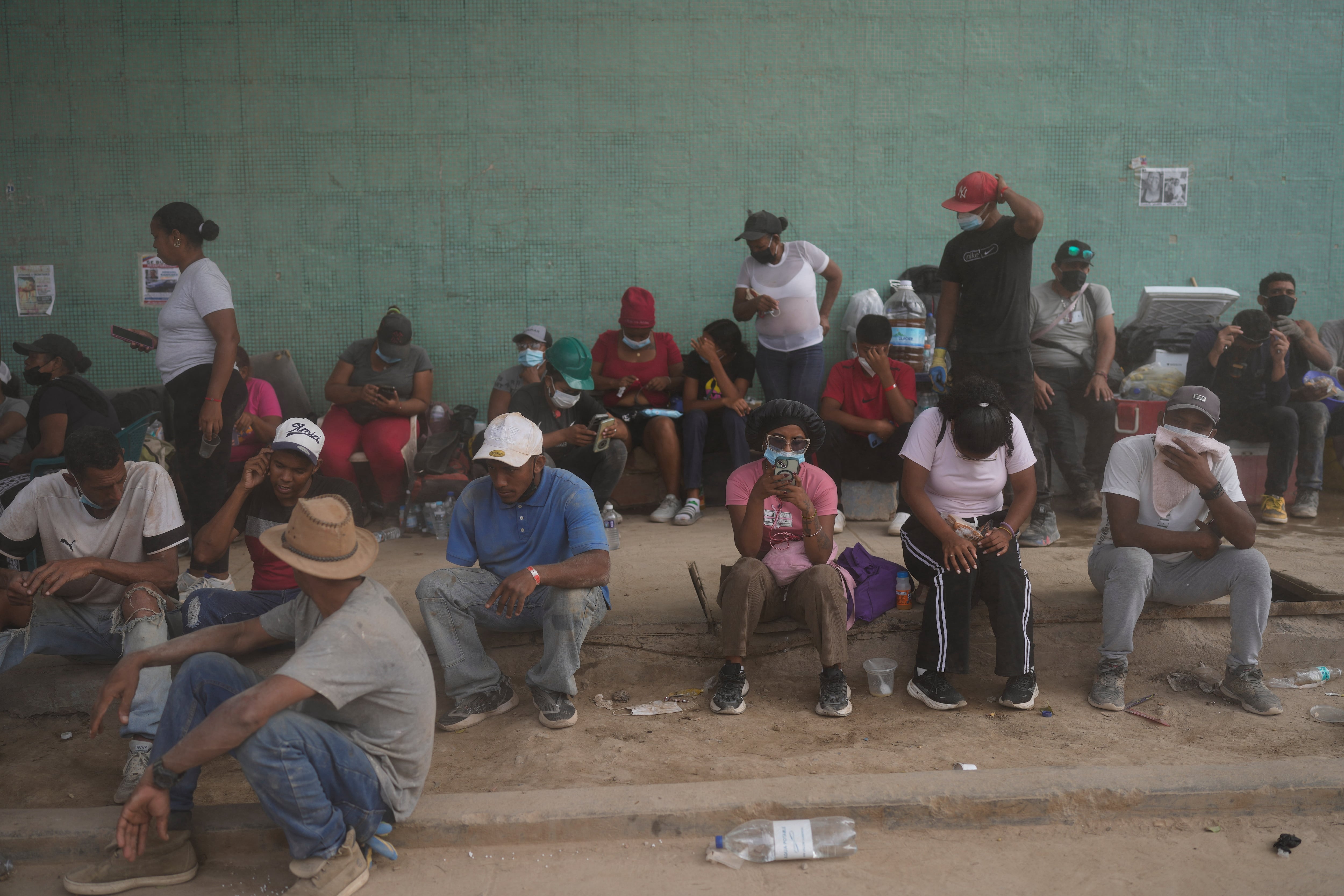 Los familiares se sientan en la acera mientras esperan a que los trabajadores retiren los escombros de los edificios derrumbados en La Guaira