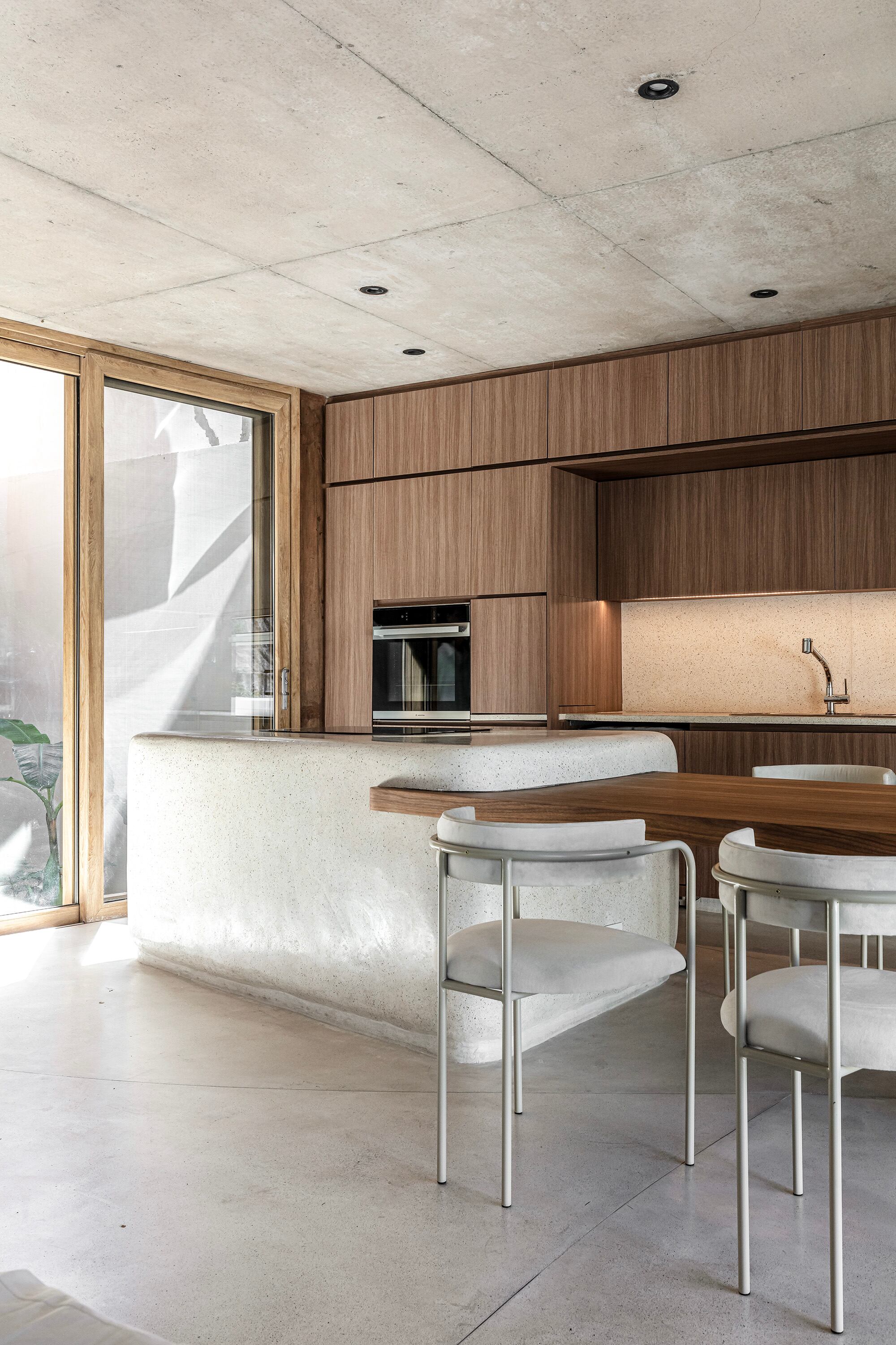 Mesa de nogal –con estructura metálica en el interior– embutida en la isla (Grizzo Studio). Las sillas fueron una elección de la dueña de casa. Carpinterias de PVC (TESATECH).