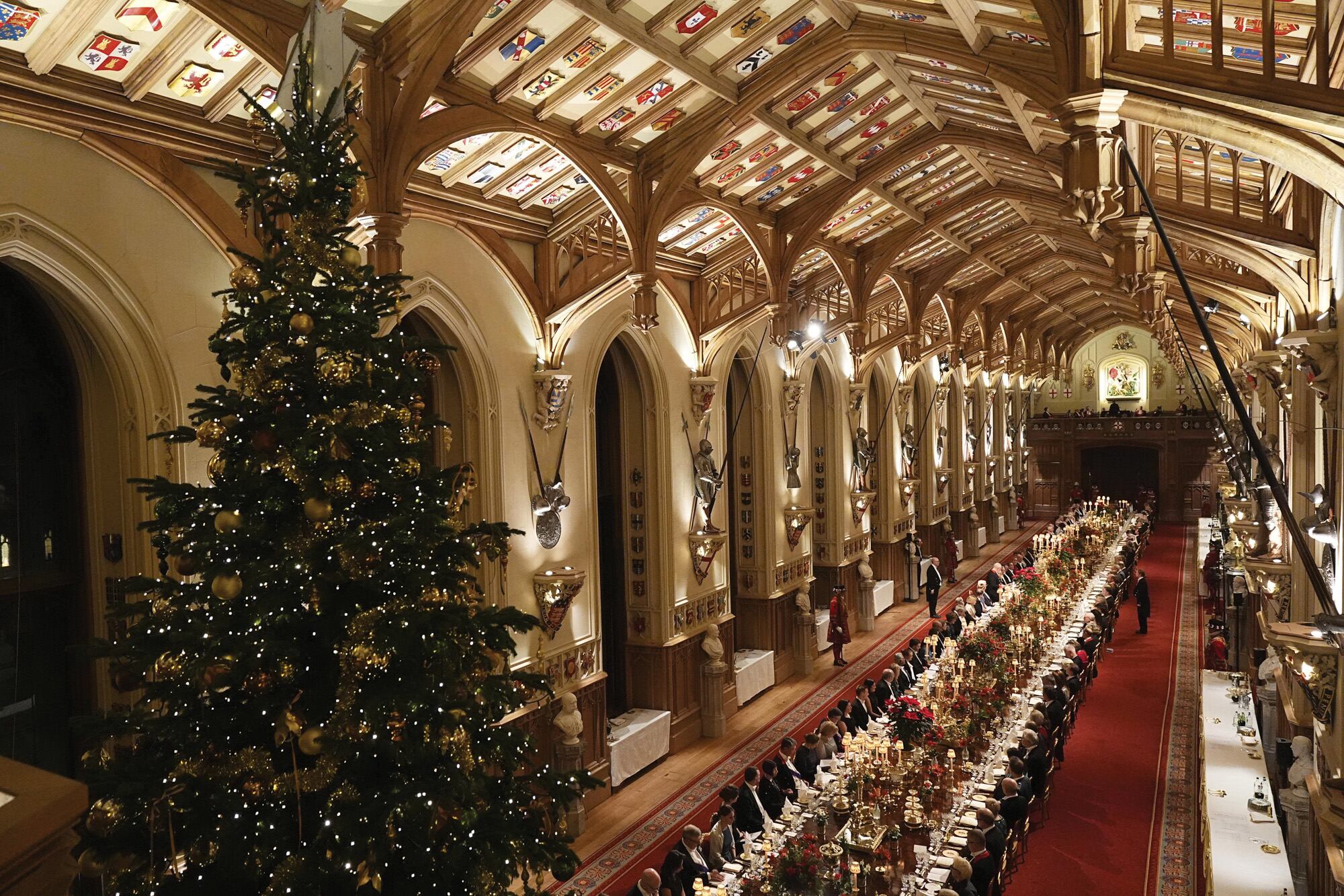 El salón St Georges’s Hall de Windsor, con el enorme abeto de 20 metros de altura y la mesa de 45 metros de largo, decorada con 158 velas y flores rojas recogidas de los propios jardines del castillo. Se dispuso un servicio de para 152 comensales, no para los 160 habituales, porque fue necesario hacer espacio para la decoración navideña