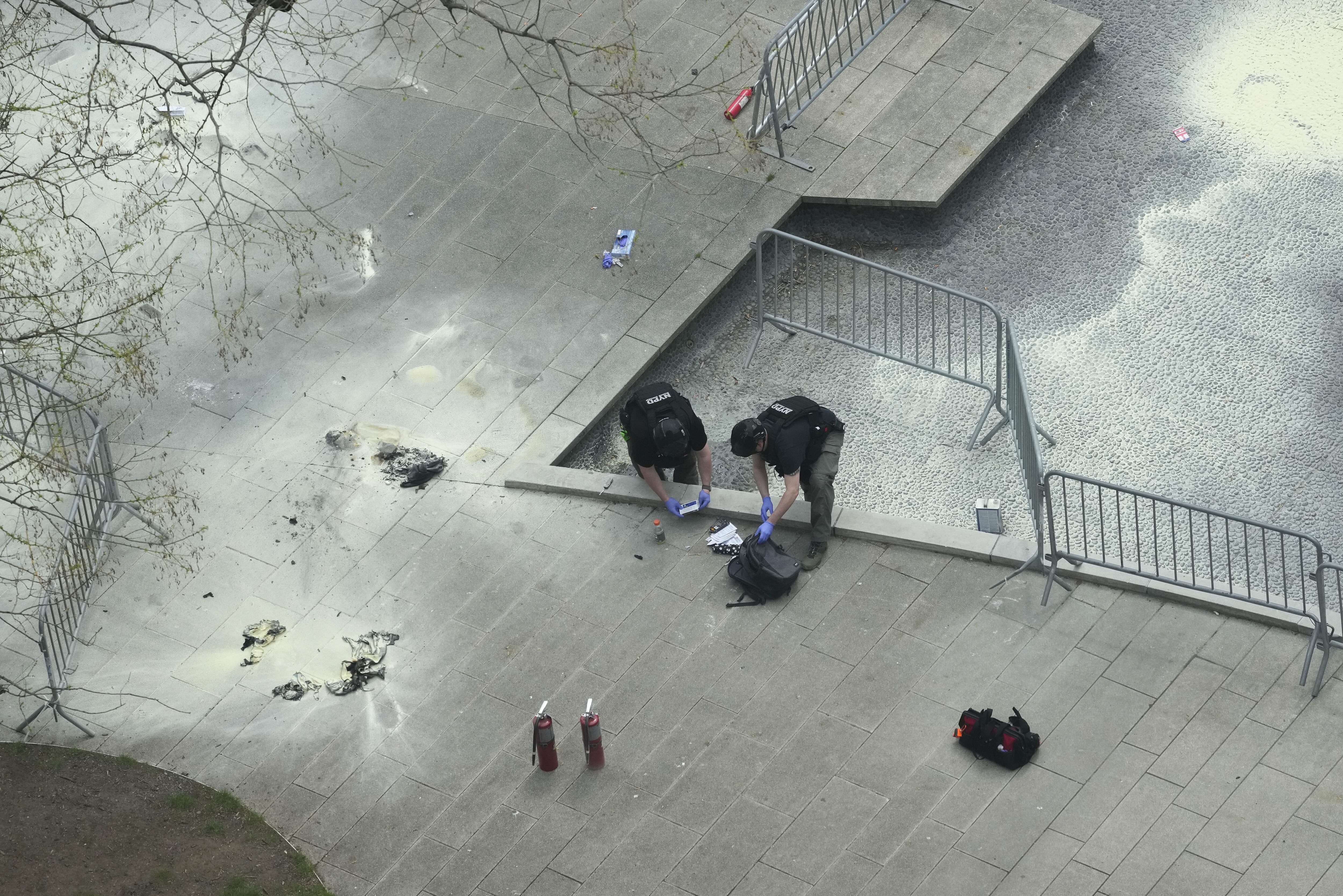 Agentes de policía de Nueva York inspeccionan una mochila dejada en el lugar donde un hombre se prendió fuego en un parque fuera de la corte criminal de Manhattan, el viernes 19 de abril de 2024, en Nueva York. 