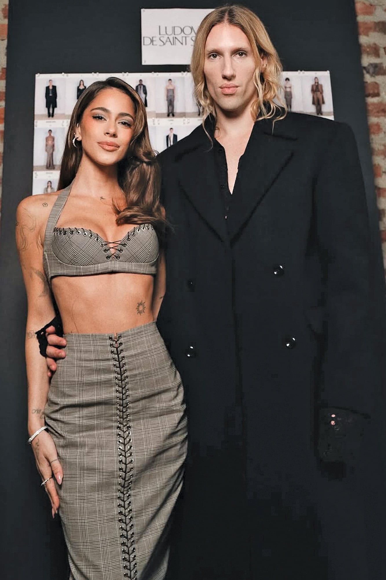 En marzo de 2025 comenzó el vínculo de Tini con el diseñador belga. Invitada a su desfile durante la Semana de la Moda de París, la cantante asistió con un exclusivo conjunto de la colección Otoño 2025: un top tipo corset y una falda midi a cuadros grises, ambos intervenidos con los característicos cordones metálicos de la firma