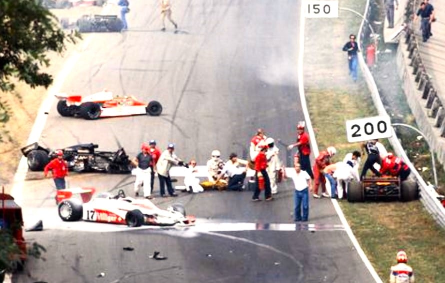 Ronnie Peterson, ya fuera del Lotus, es asistido en el piso, junto a otros pílotos; detrás, el Lotus negro N° 6