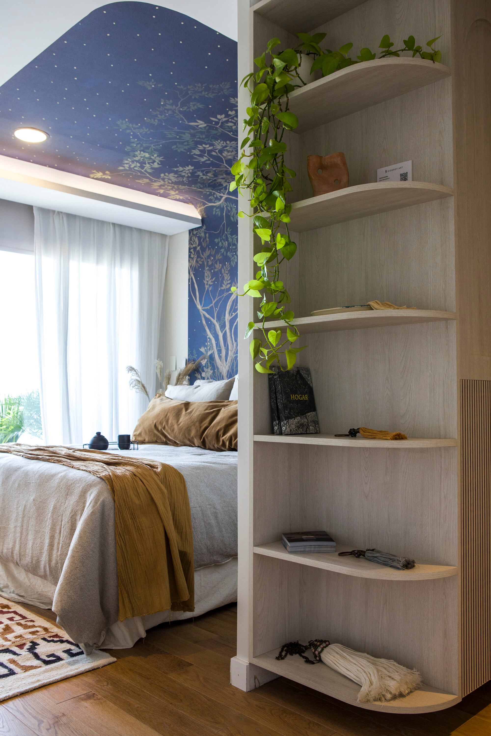 Una estantería le suma espacio de guardado a la antesala del dormitorio. Las cortinas de gasa de algodón son de confección propia.