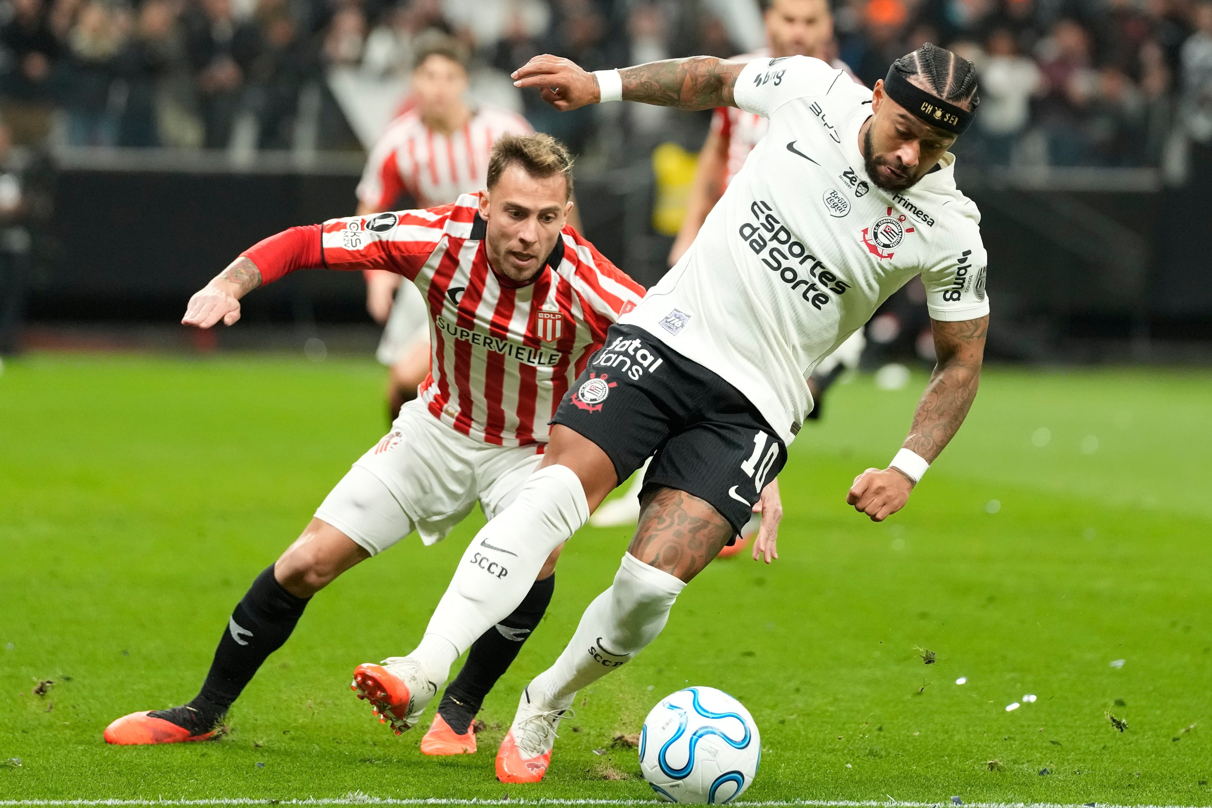 Menphis Depay lleva la pelota ante la presión de Lucas Piovi en la visita de Estudiantes de La Plata a Corinthians por la Copa Libertadores
