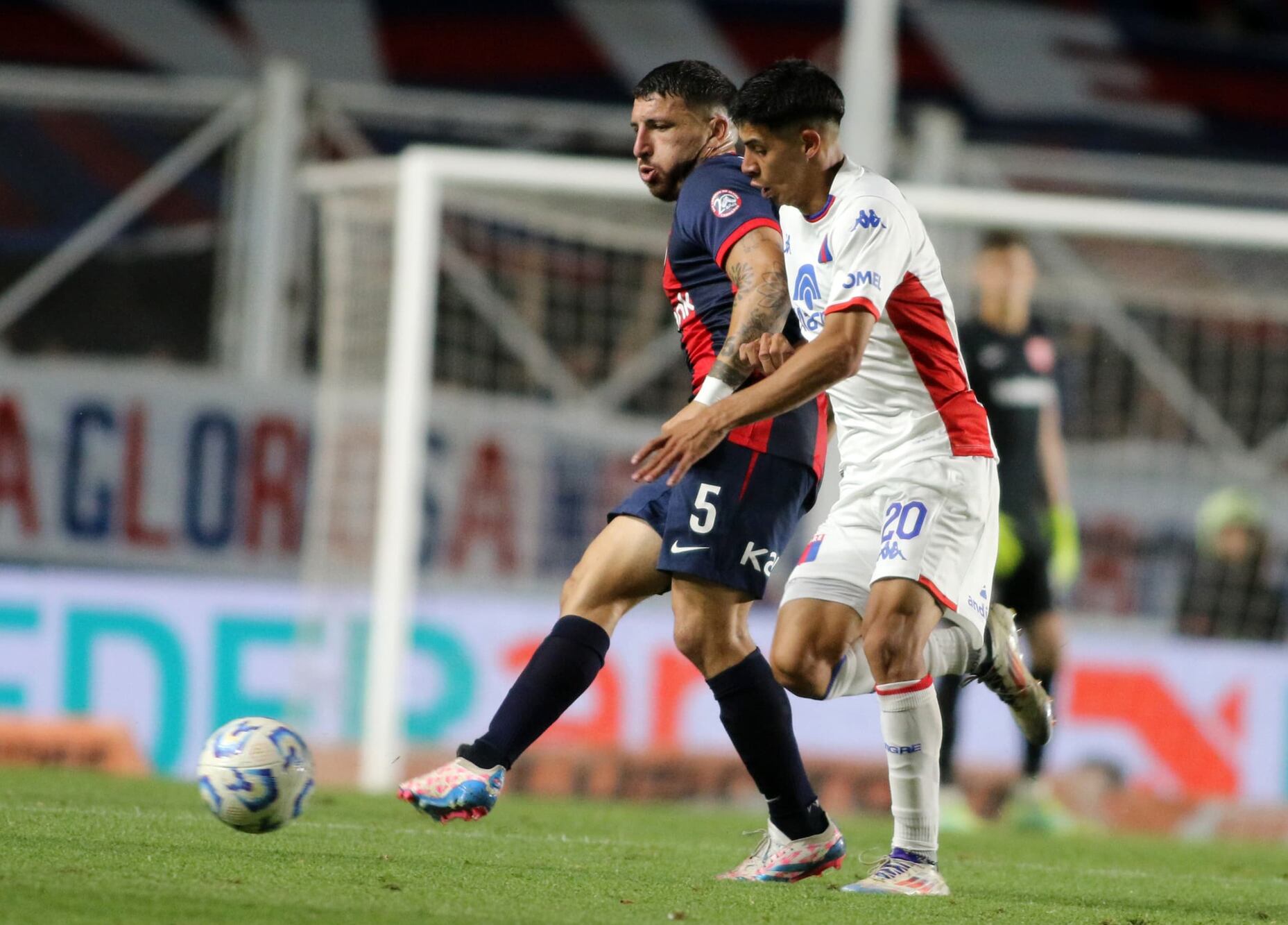 Eric Remedi, de San Lorenzo, hace un pase ante Tomás Galván, de Tigre