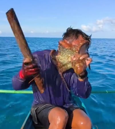 Las impactantes imágenes muestran al pescador intentando desesperadamente arrancarse el molusco de la cara