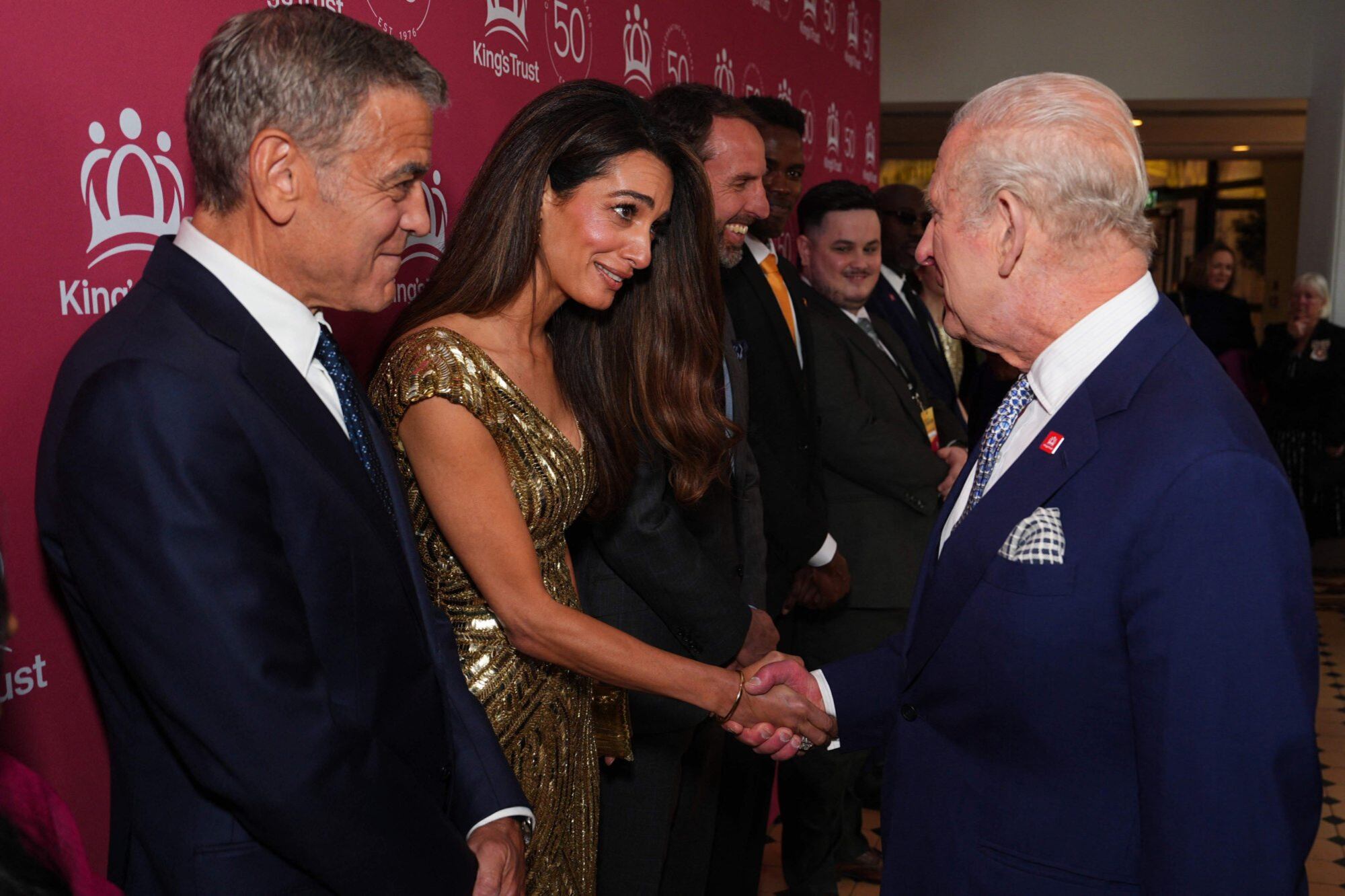 Amal Clooney saluda al rey Carlos III bajo la atenta mirada de George Clooney durante la celebración por el 50° aniversario de The King’s Trust