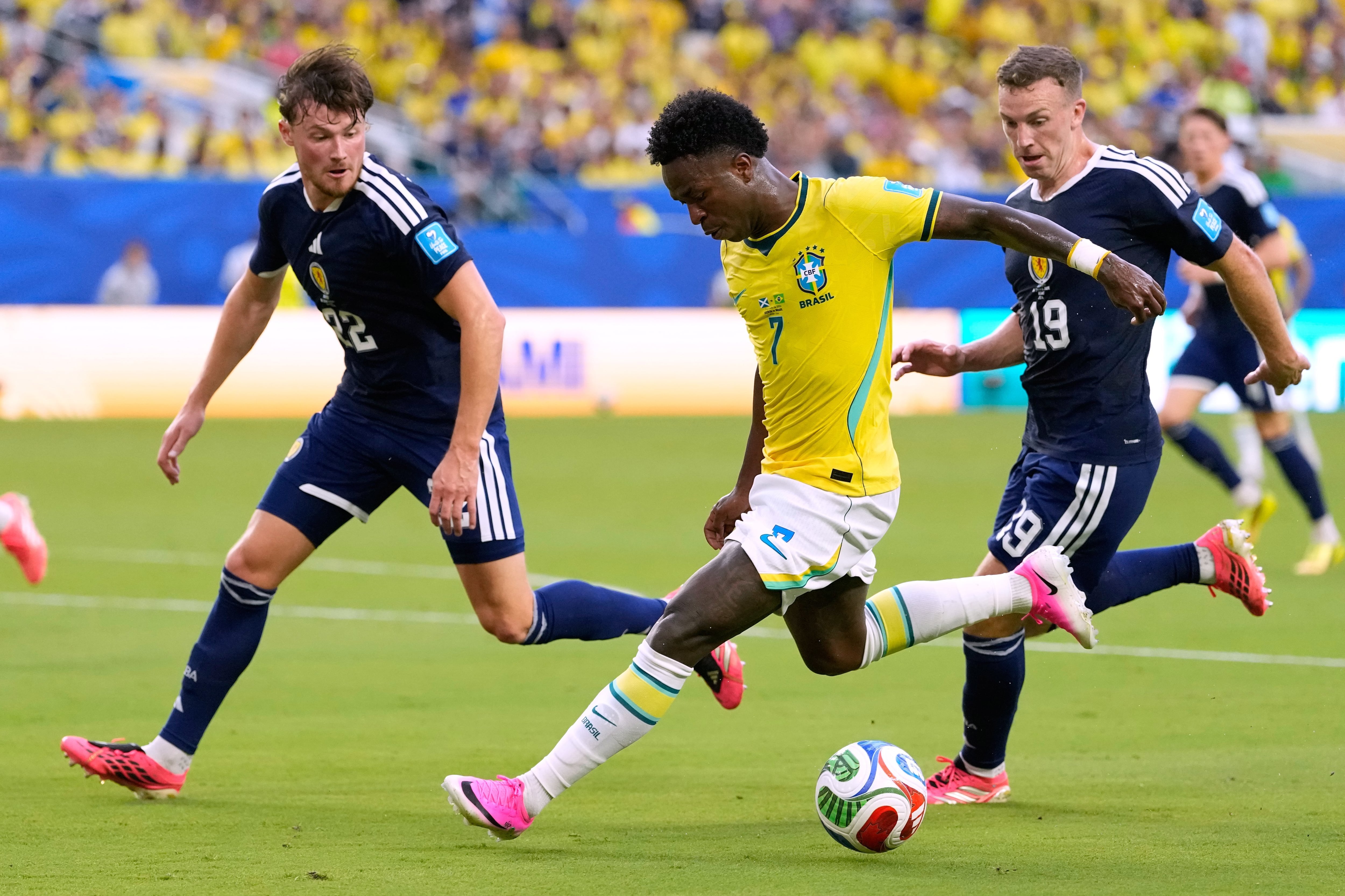 Vinicius Junior, un peligro permanente; aquí, lo marcan Nathan Patterson y Lewis Ferguson (AP Photo/Rebecca Blackwell)