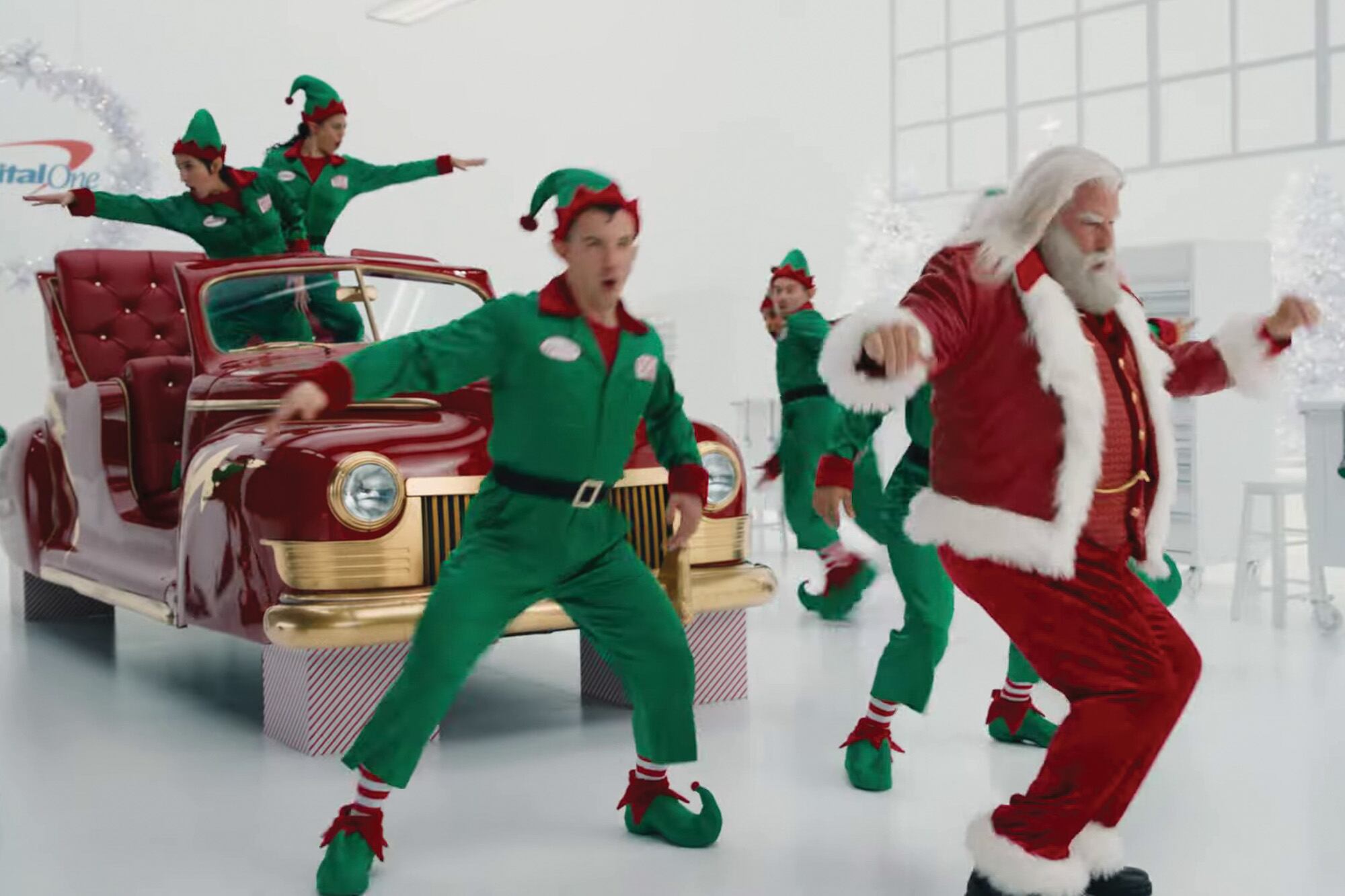 Travolta como Papá Noel, rodeado de elfos mecánicos que ponen a punto su trineo