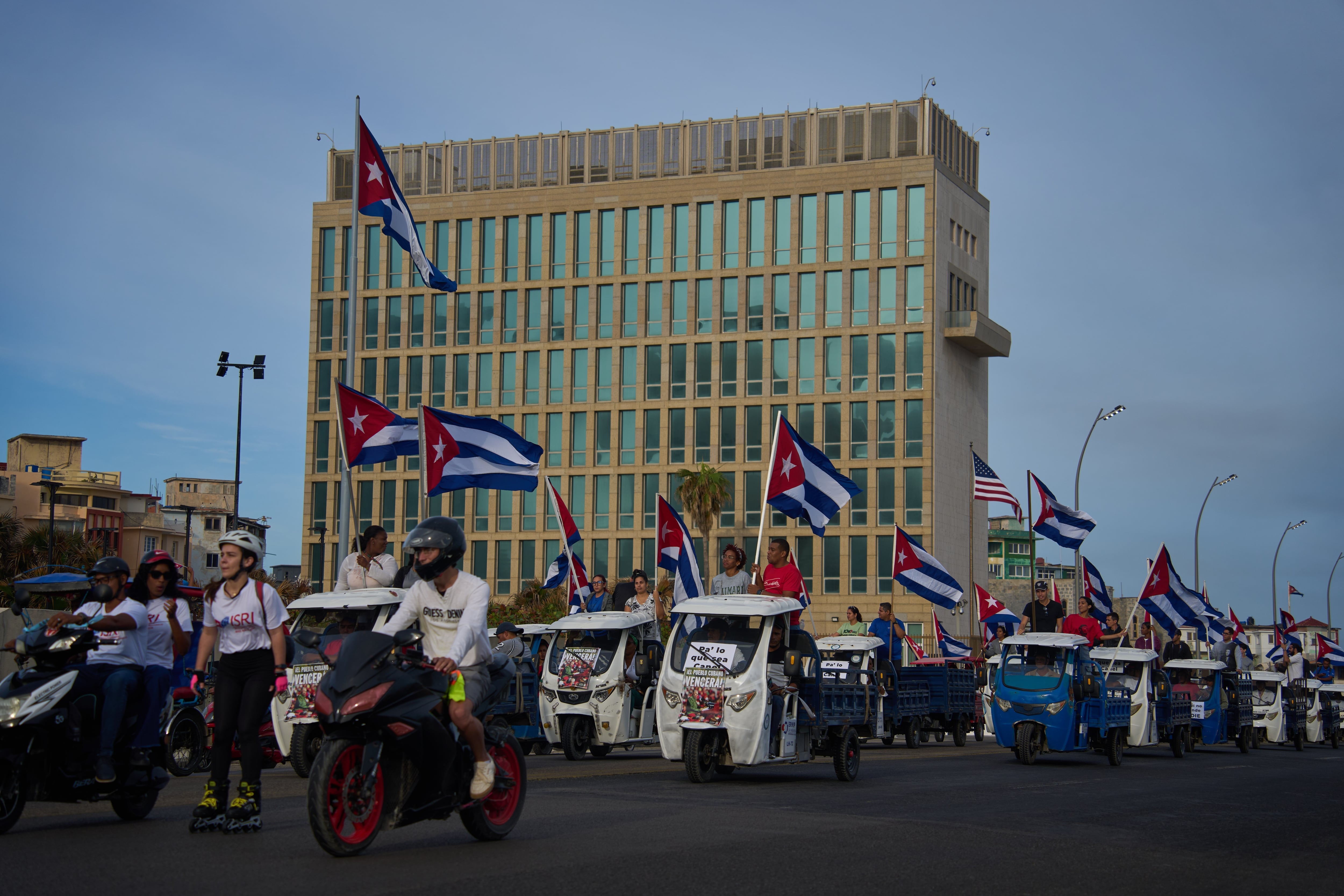 Varias personas pasan en vehículos eléctricos frente a la embajada de Estados Unidos durante una marcha juvenil antiimperialista, el 2 de abril de 2026