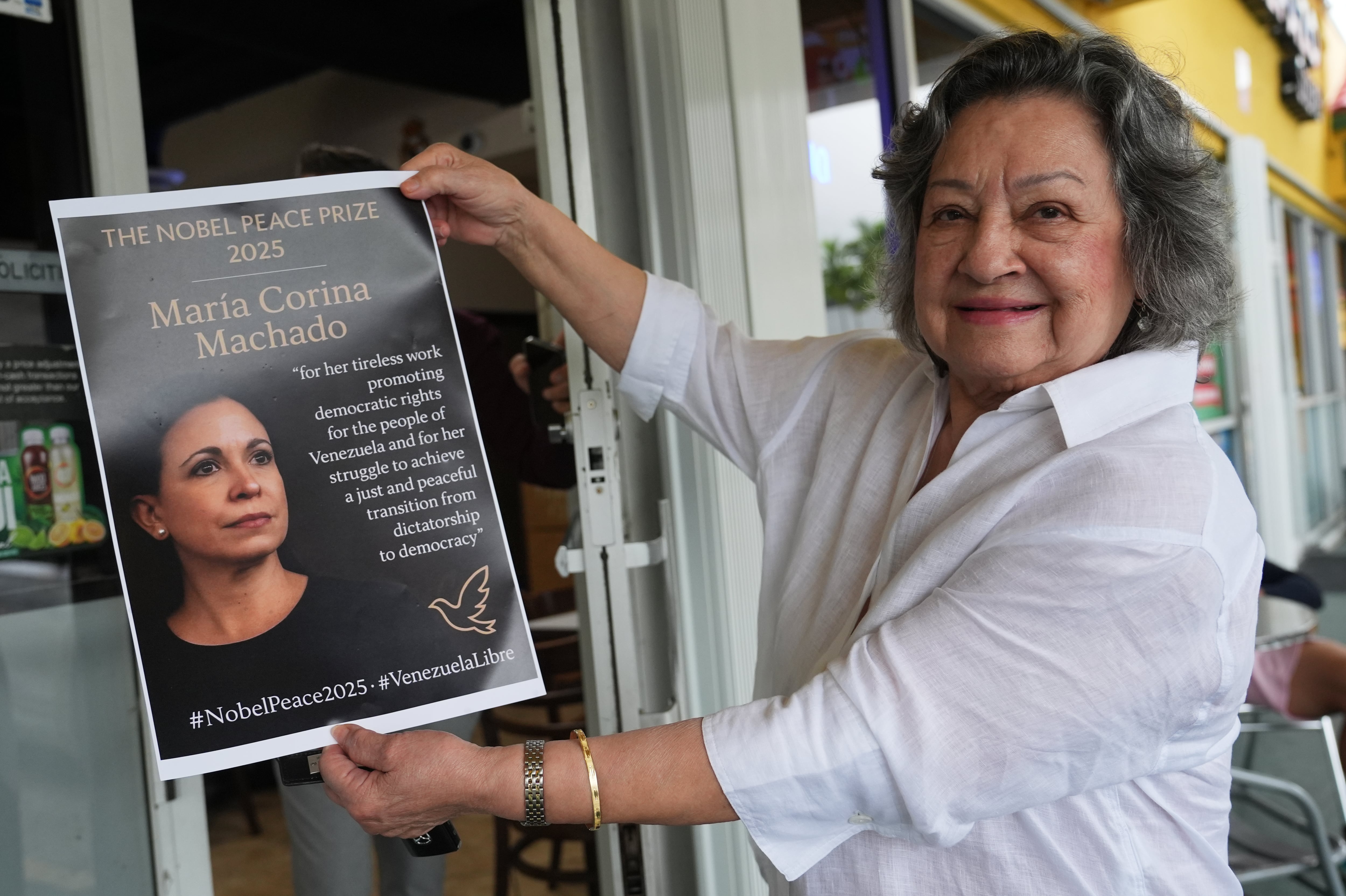 Iris Wilthew sostiene un cartel en apoyo a la líder opositora venezolana María Corina Machado tras recibir el Premio Nobel de la Paz, el 10 de octubre de 2025, en Doral, Florida. (AP Foto/Lynne Sladky)