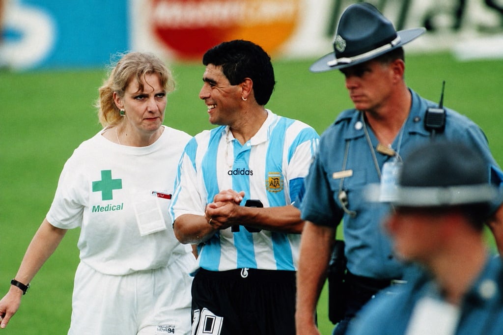 Diego Maradona deja el campo de juego del Foxboro Stadium, de Boston, junto a Sue Ellen Carpenter, la