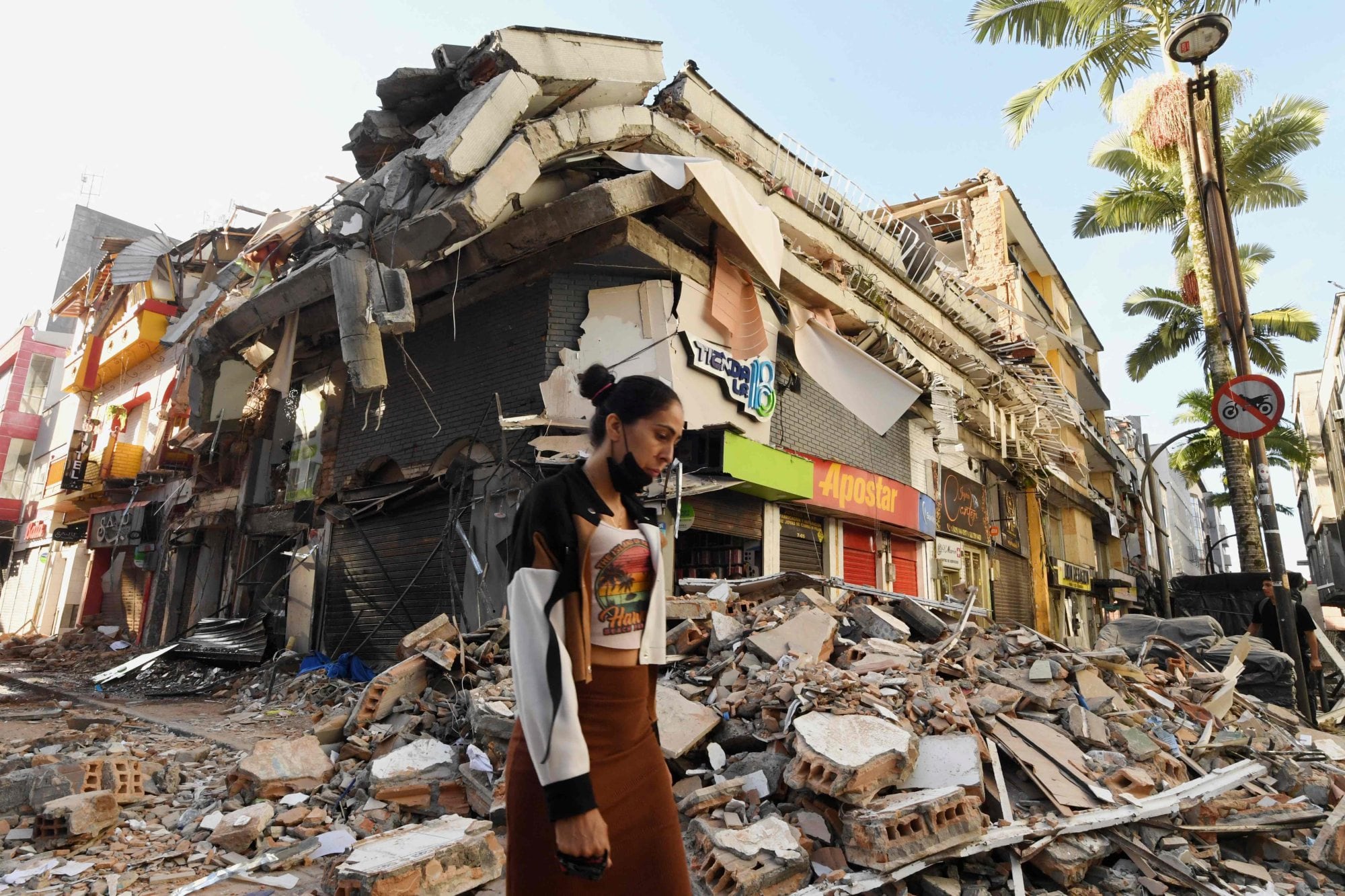 Una mujer camina entre los escombros de un edificio que colapsó durante el terremoto