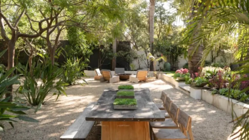 El parque que rodea la vivienda combina áreas verdes cuidadas con árboles maduros y sectores de descanso al aire libre