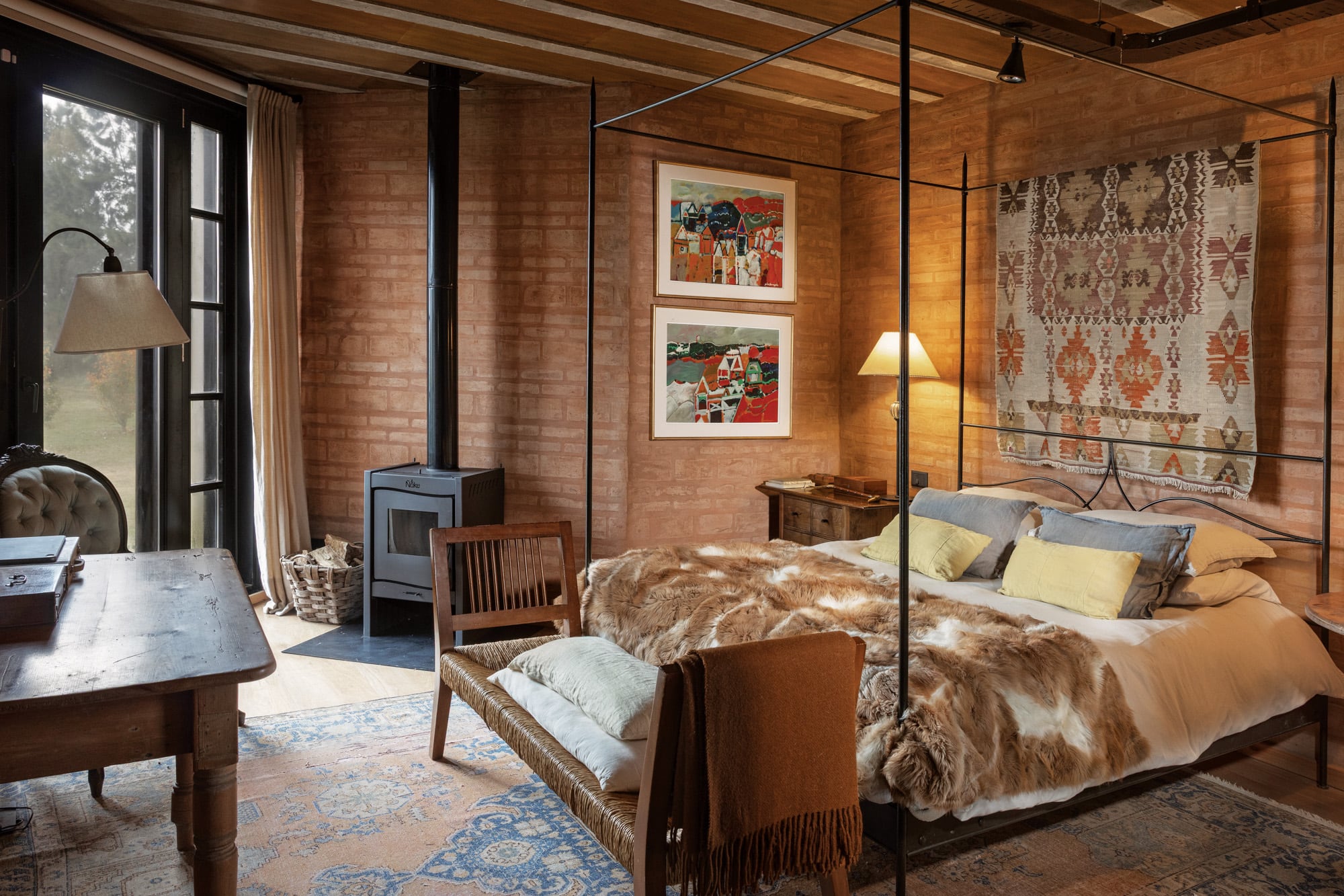 La cama y la banqueta de la habitación principal, de María de Victoria las Carreras. A la alfombra persa la llevaron de su casa de Buenos Aires. Detrás de la cama, un kilim antiguo (Facundo Lhez) y al costado, dos cuadros de Luis Barragán