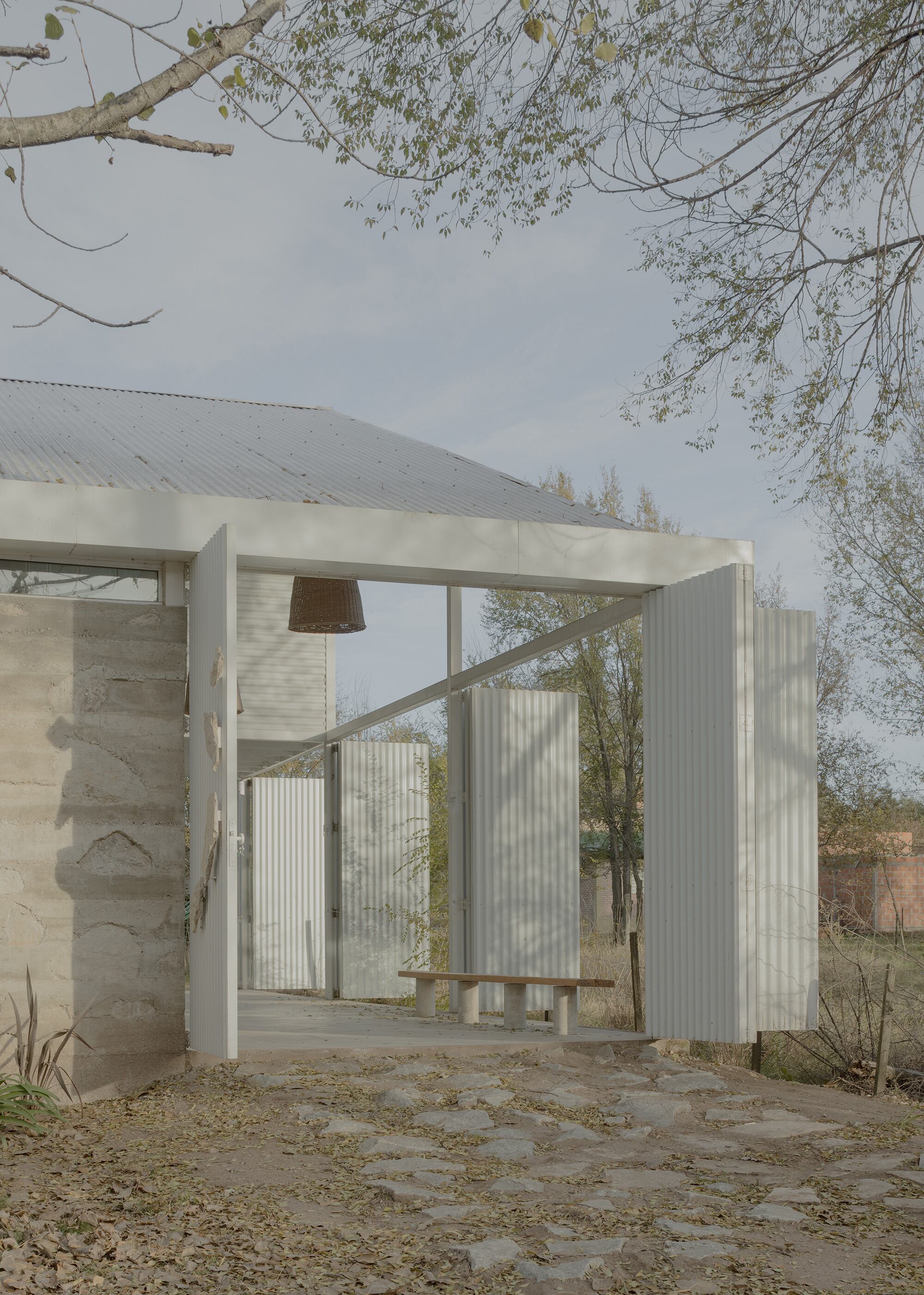 El acceso principal se ve desde la calle y da inicio a la fachada metálica que se repite en los laterales y el fondo.