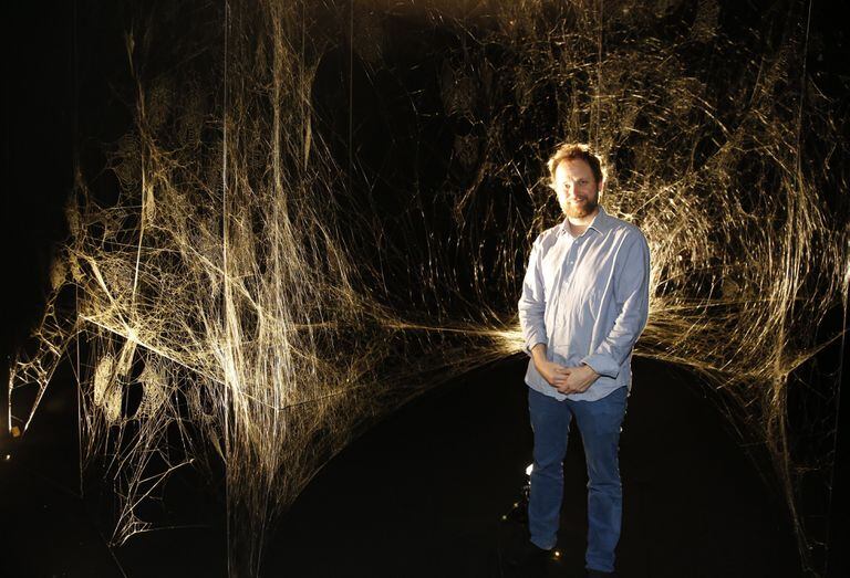 Tomás Saraceno junto a la tela construida por miles de arañas en el Moderno